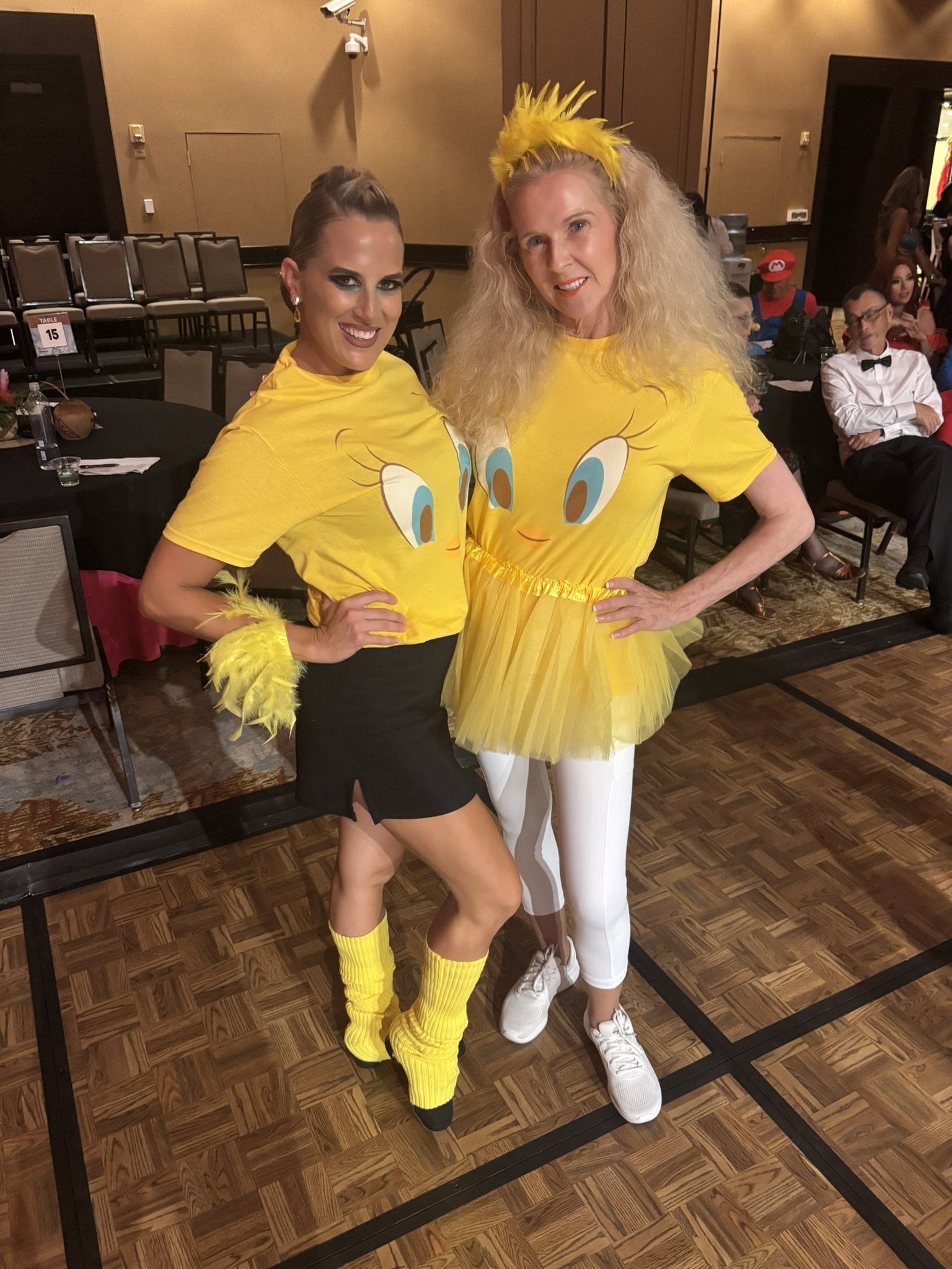 Amy Hanson and another dancer posing in matching yellow cartoon-bird costumes on a ballroom floor
