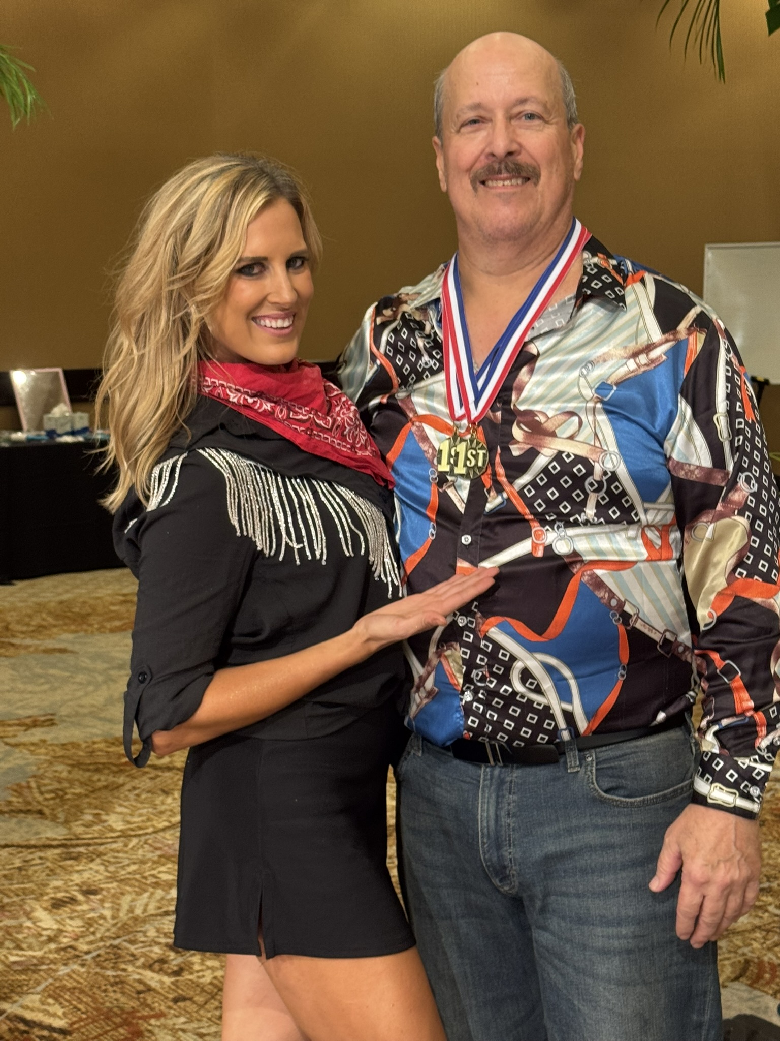 Amy Hanson in a black fringed western outfit and red bandana smiling beside her student Jerry, who wears a patterned shirt and a first-place medal