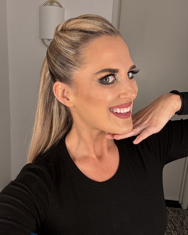 Amy Hanson of Ballroom by Amy smiling, hand under her chin, in a black top