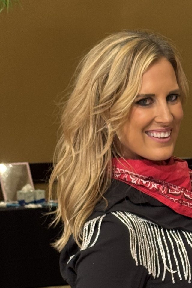Amy Hanson of Ballroom by Amy smiling in a black Western fringe shirt and red bandana